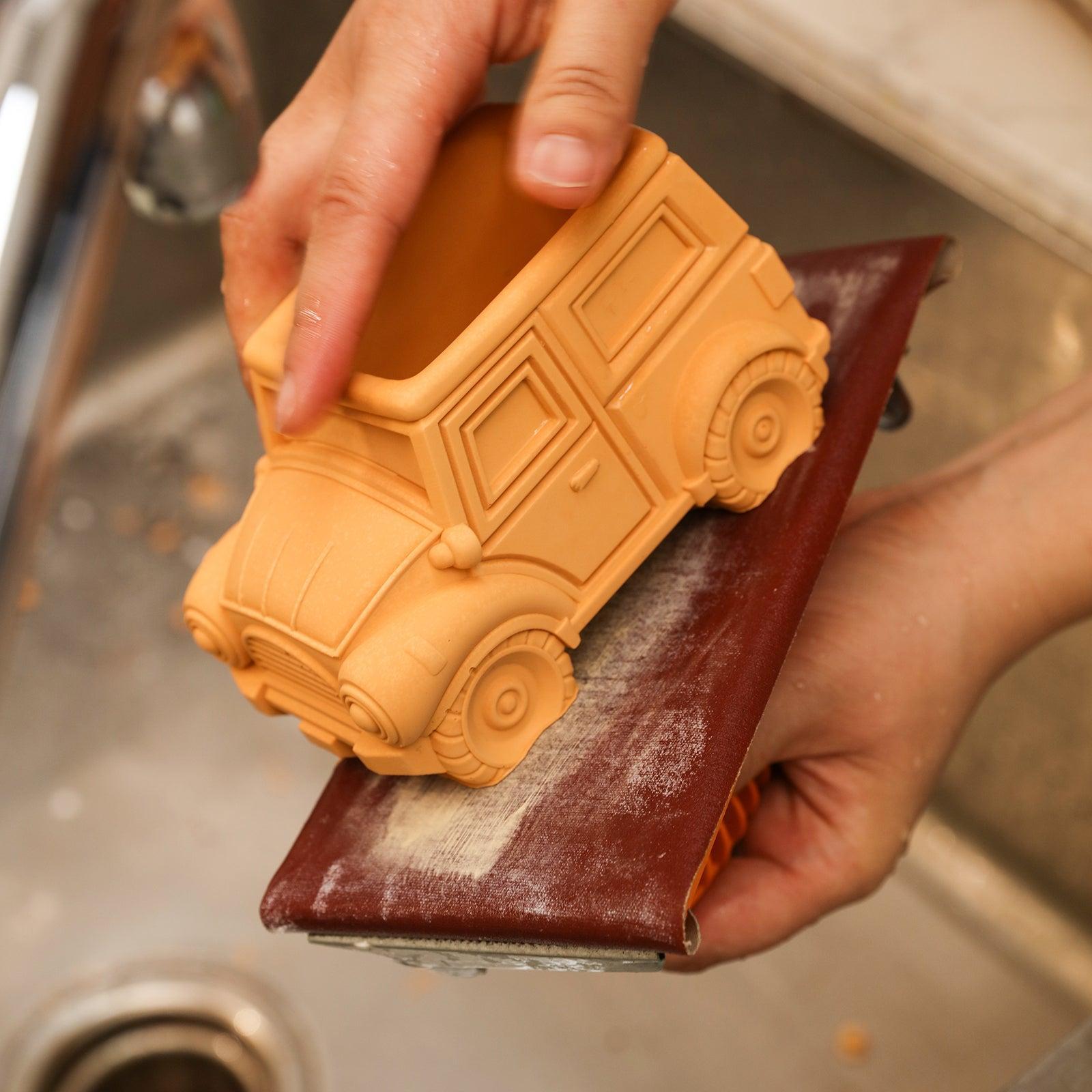 Sand the bottom of Vintage Off-Road Car Plant Pot Concrete using tools under running water - Boowan Nicole