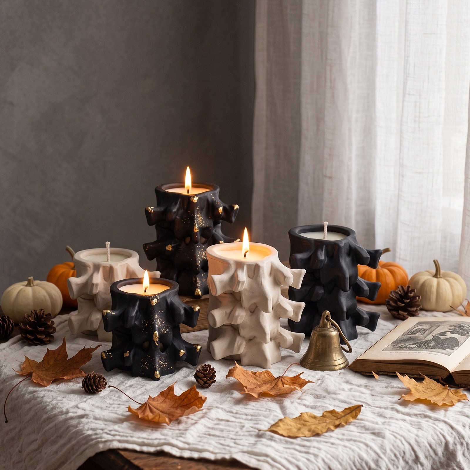 Black and white Haunted Spine candle jars styled with pumpkins and autumn maple leaves for Halloween decor - Boowan Nicole
