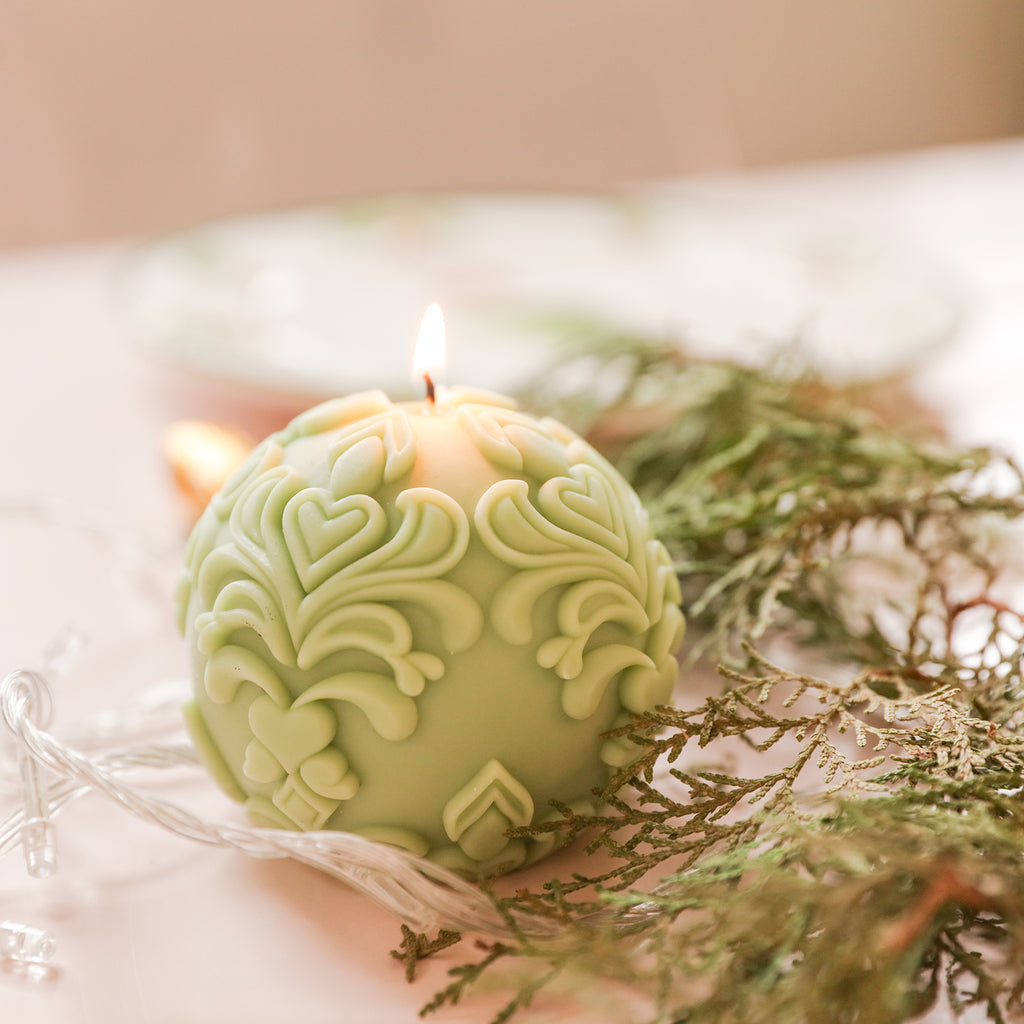 Illuminating space with a lit sphere patterned relief candle.