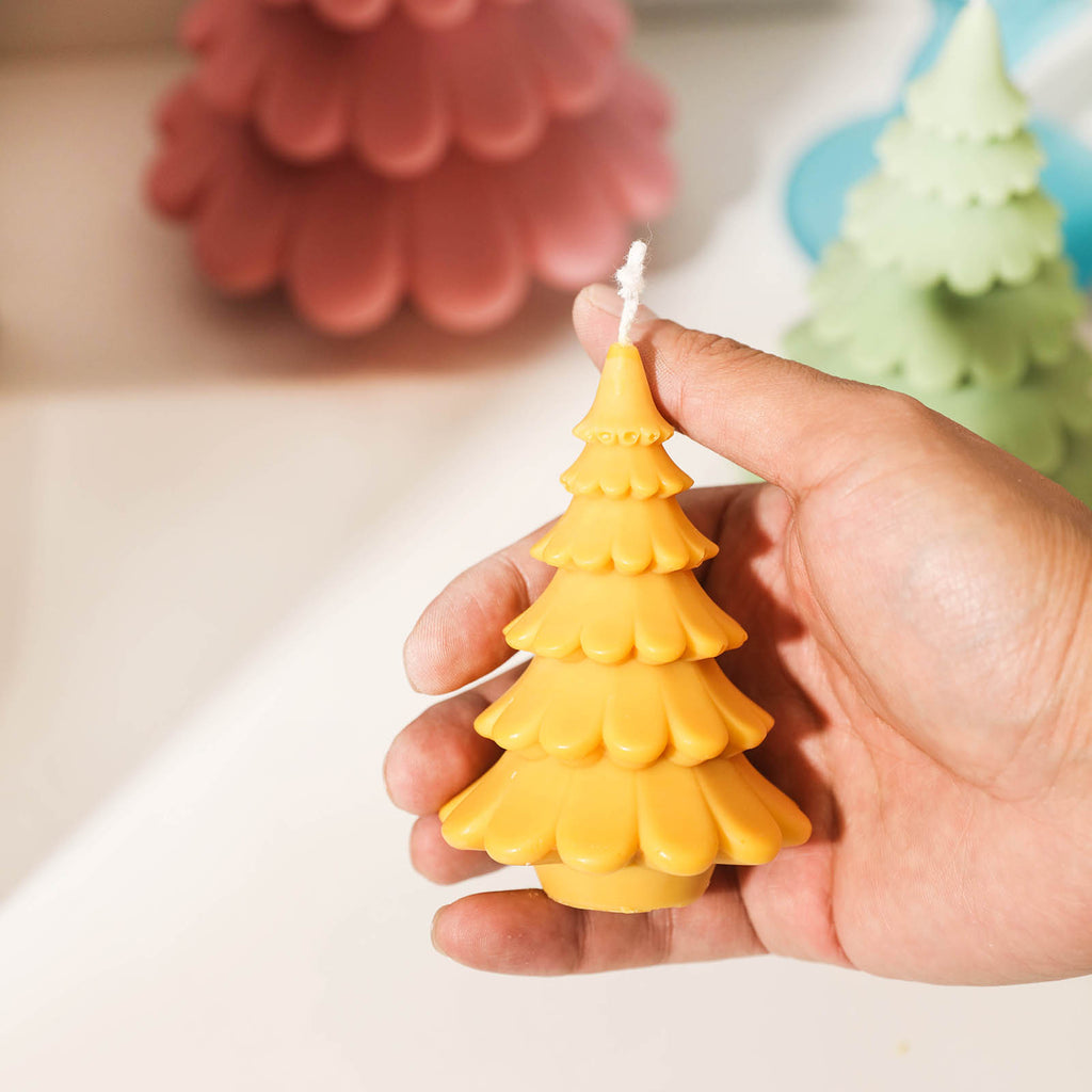 Yellow 4-inch Christmas tree candle placed in hand display, designed by Boowan Nicole.