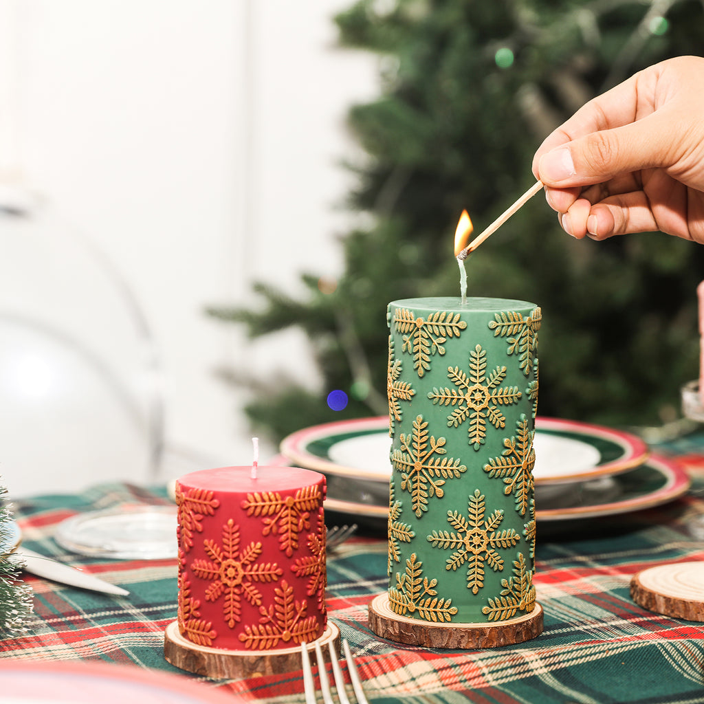 There are long green snowflake relief candles and short red snowflake relief candles placed on the wooden tray on the dining table.