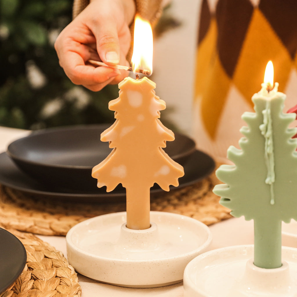 Light the yellow Christmas tree-shaped tapered candles with white accents on the dining table.