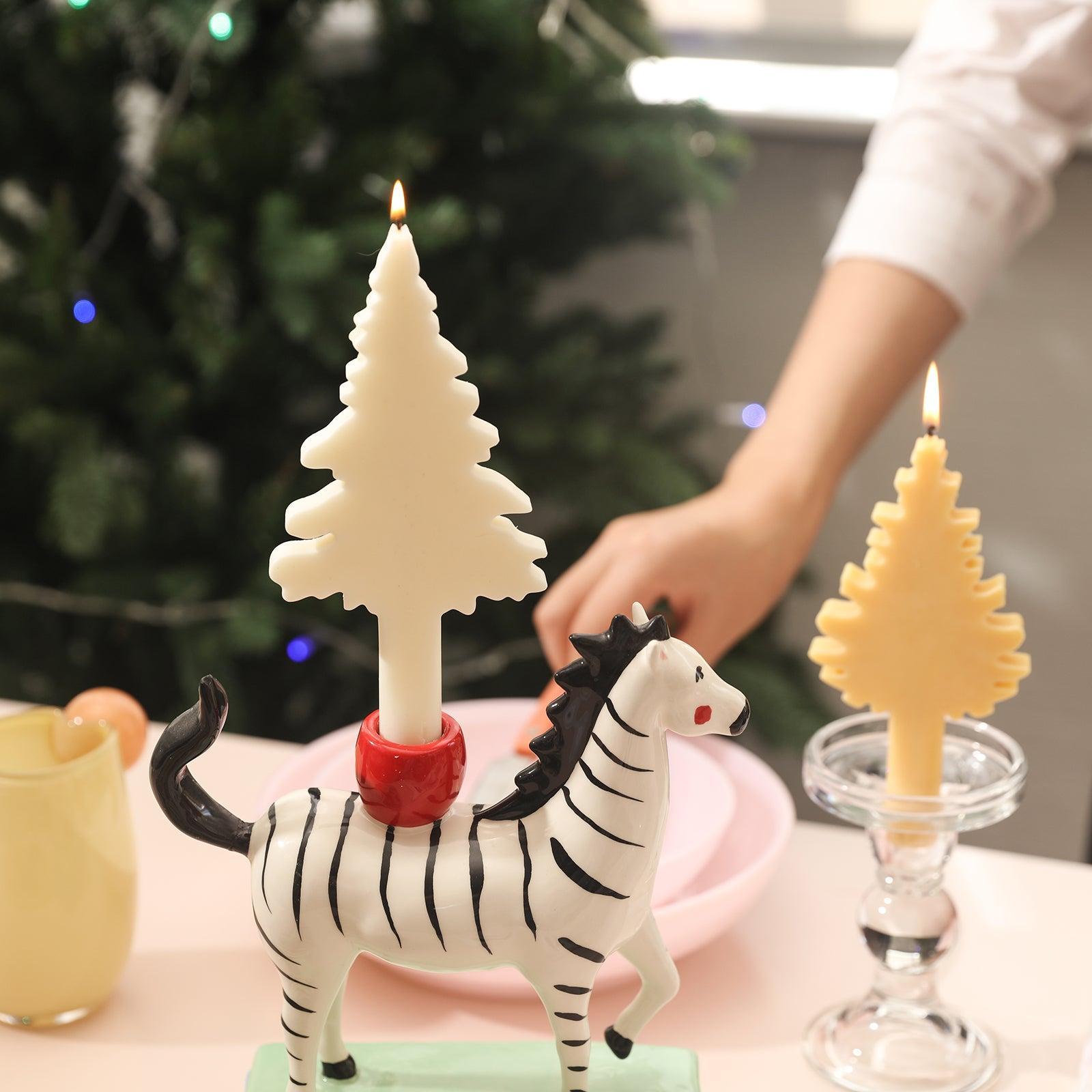 Lighted Christmas tree candles in zebra candle holders and yellow Christmas tree candles in crystal candle holders placed on the dining table.