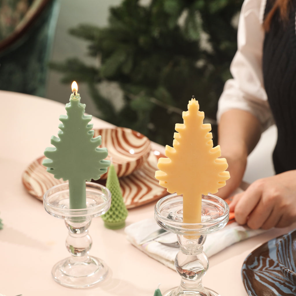 Green and yellow Christmas tree-shaped candles are placed on the crystal candlesticks on the dining table.