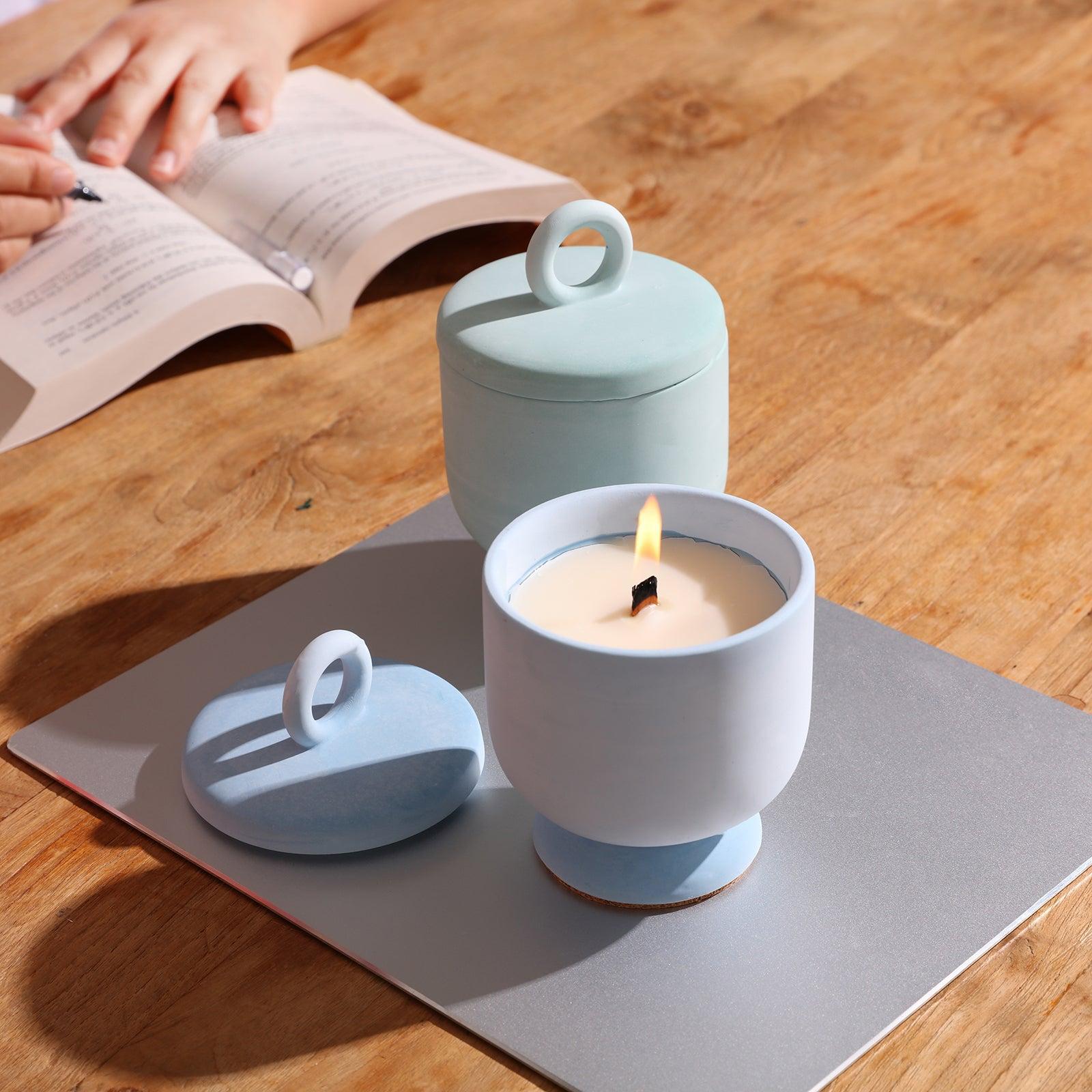 Lighted blue Chalice Tall Candle Jar next to book - Boowan Nicole