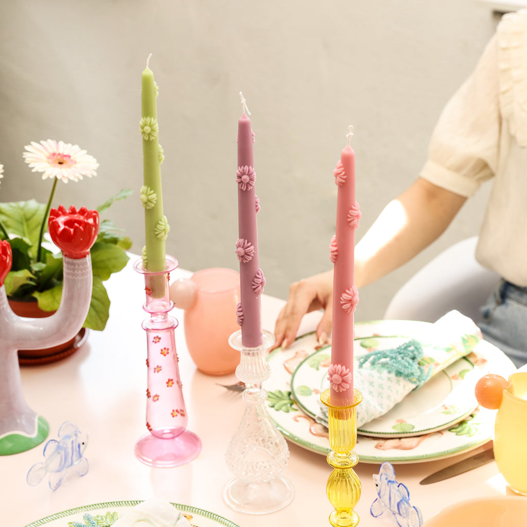 Green, purple and pink tapered candles are placed on the crystal candle holders of the dining table to add interest, designed by Boowan Nicole.