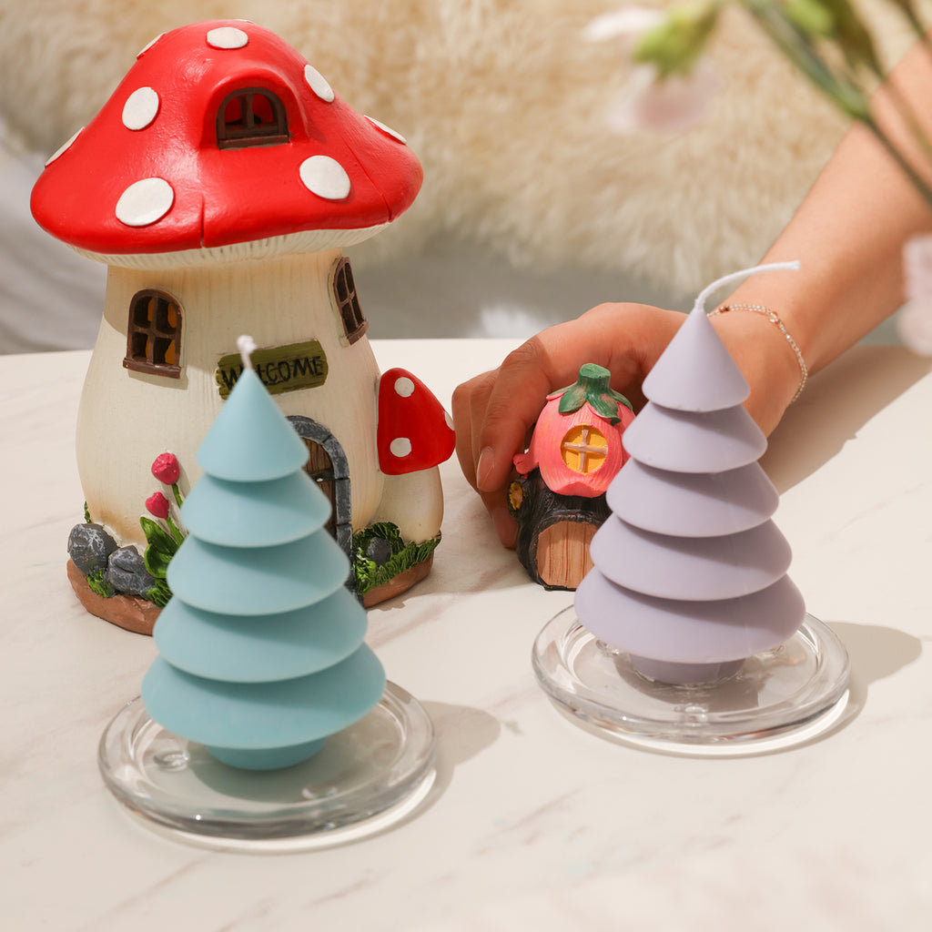 Light blue and purple layered Christmas tree candles are placed on the tabletop crystal tray, with mushroom house-shaped ornaments placed behind it - Boowan Nicole