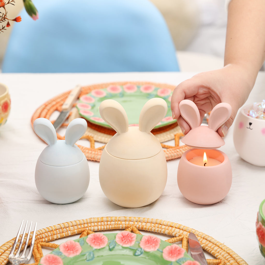 Three Easter Bunny candle jars placed on the table, one of which is lit