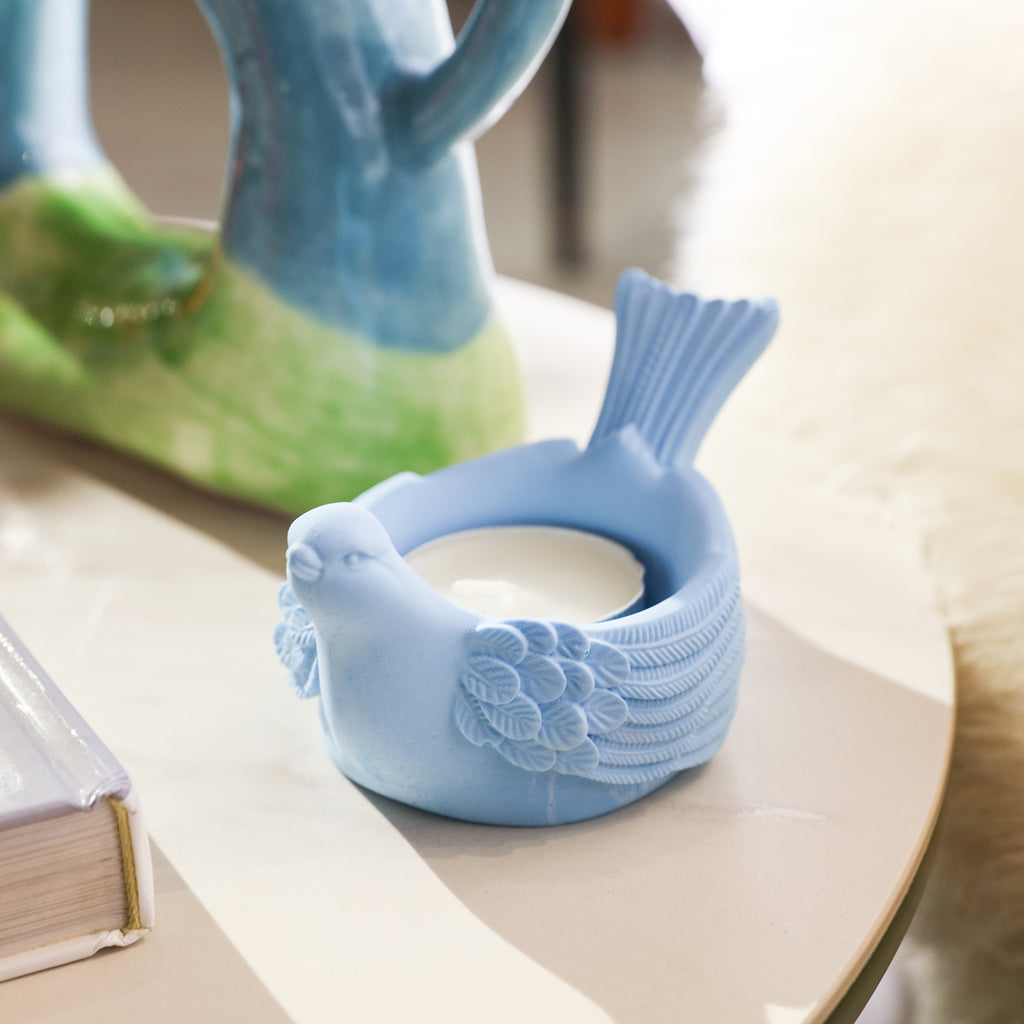 A blue tealight candle holder placed on a tabletop.