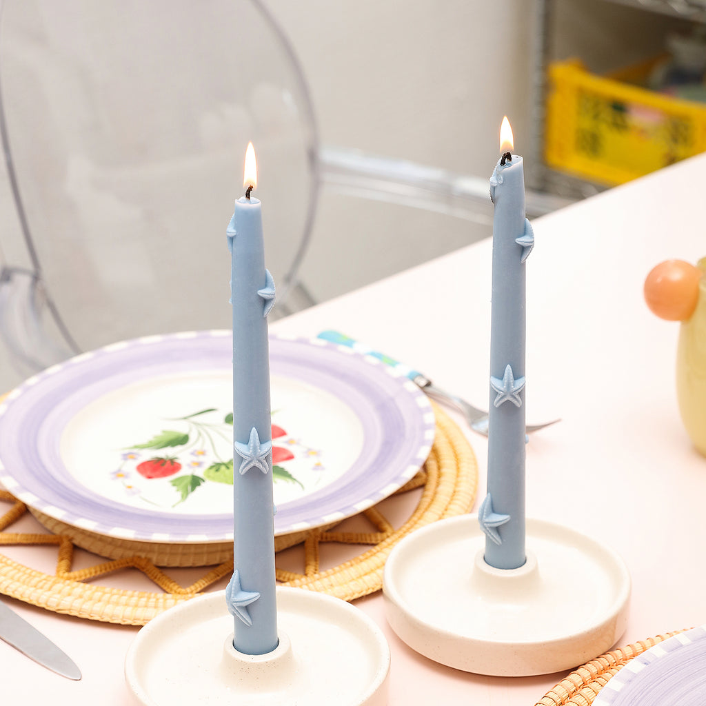 Ocean series taper candles being lit on the dining table.