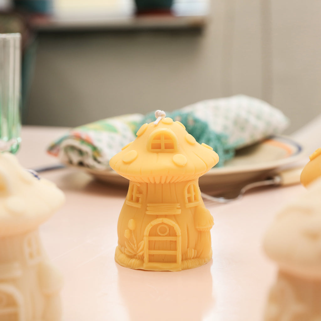 Yellow miniature mushroom house candles placed on tabletop -Boowan Nicole