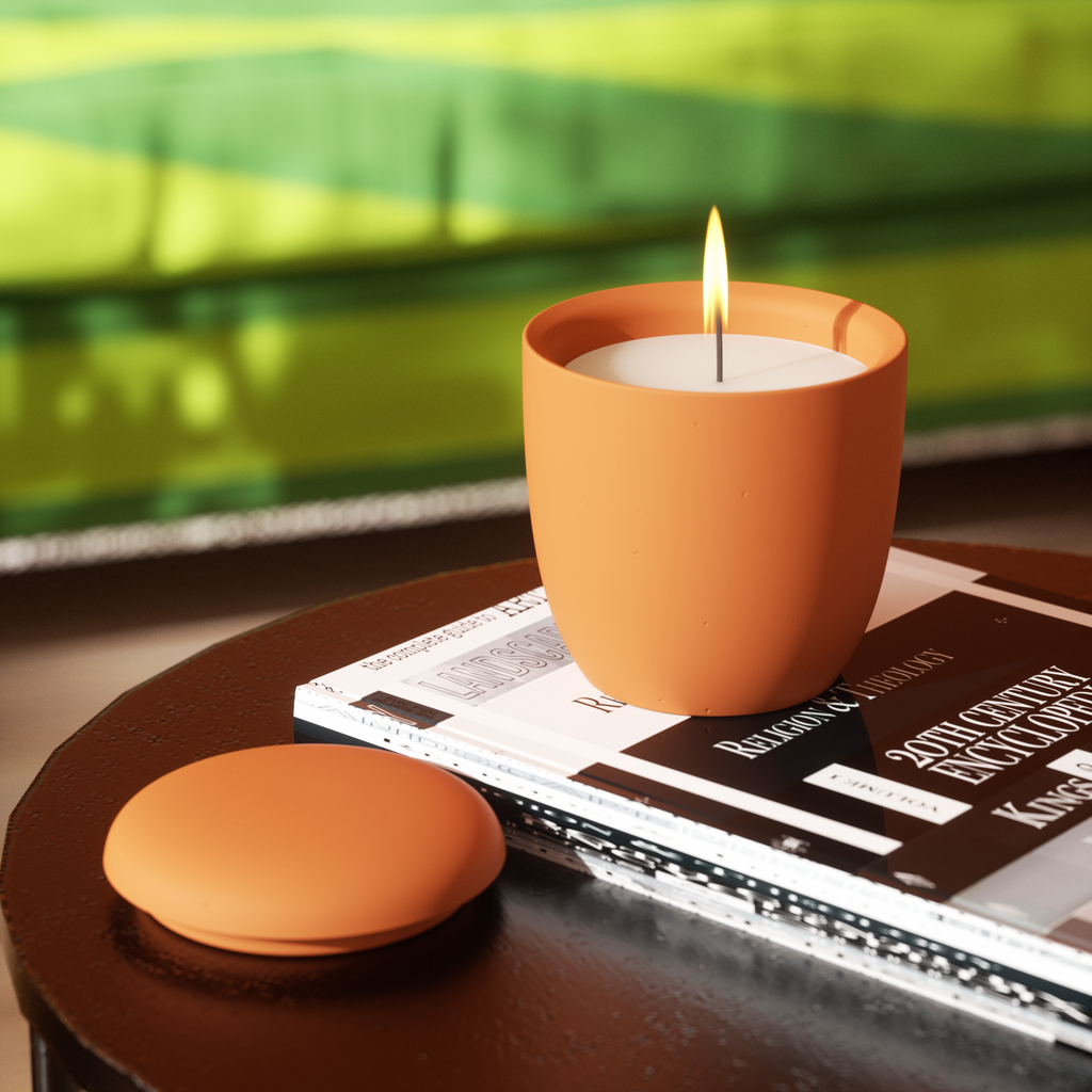 A candle lit inside an orange candle jar from boowannicole, creating a cozy atmosphere and showcasing the brand's product appeal in real-life settings.