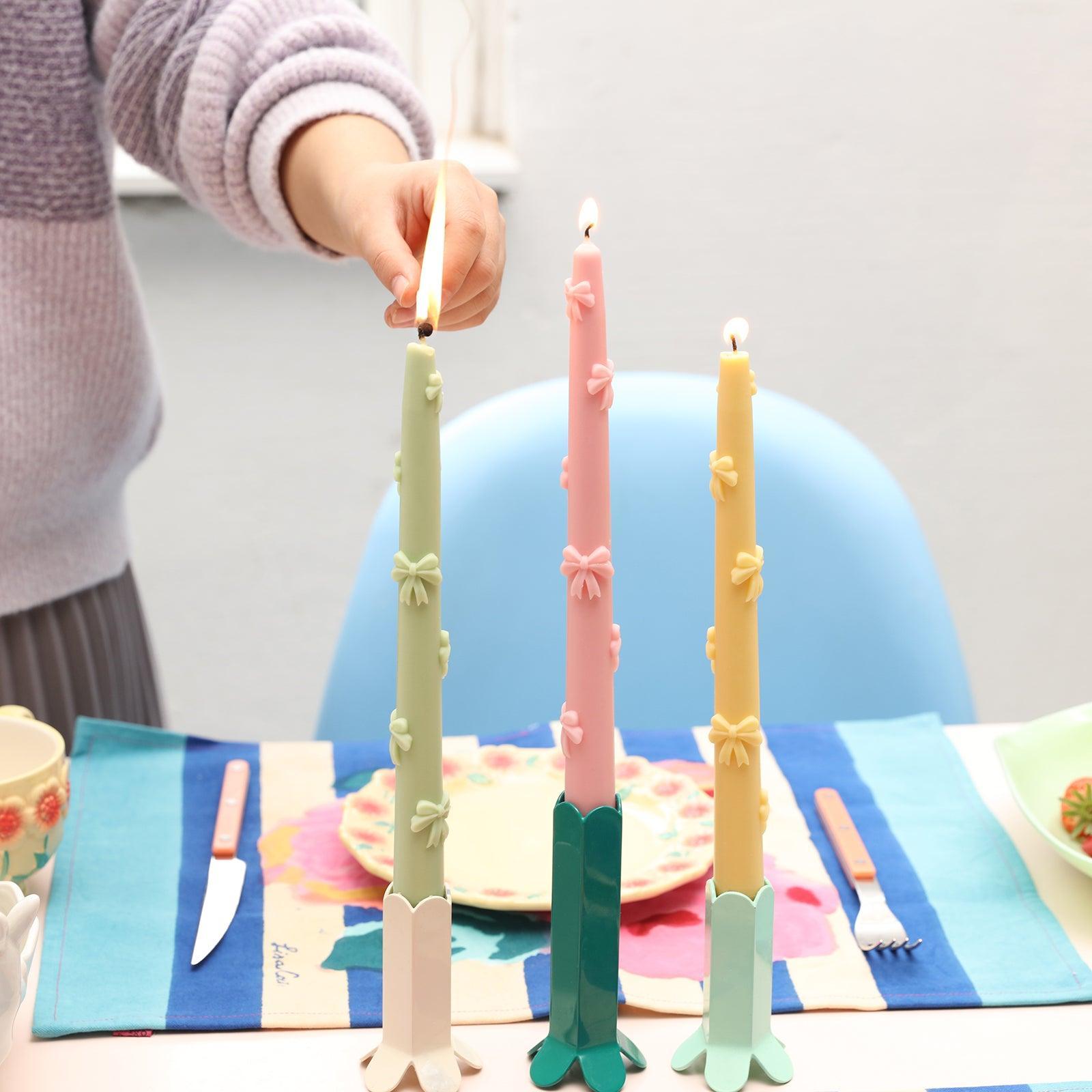 A captivating scene with three taper candles elegantly placed on candle holders, sequentially lit for a warm ambiance.