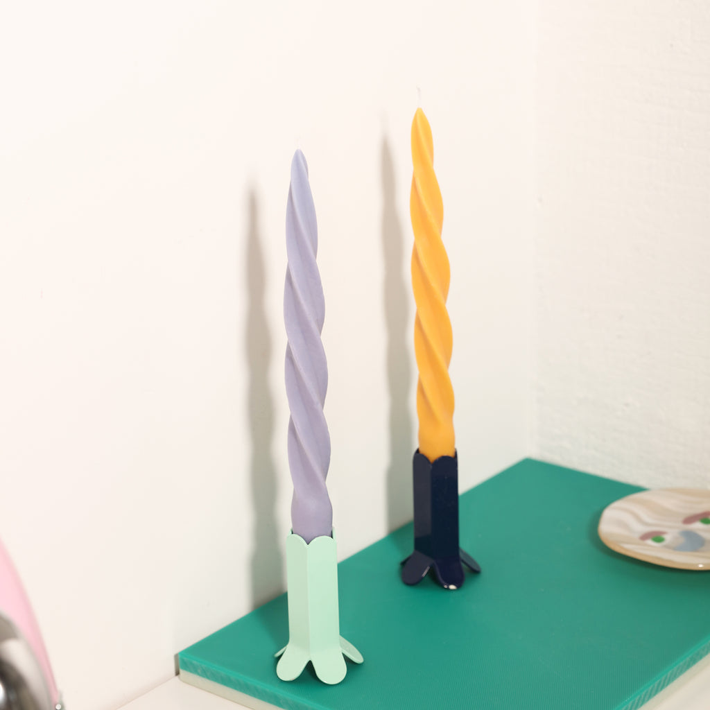 One purple and one yellow candle elegantly displayed on the table