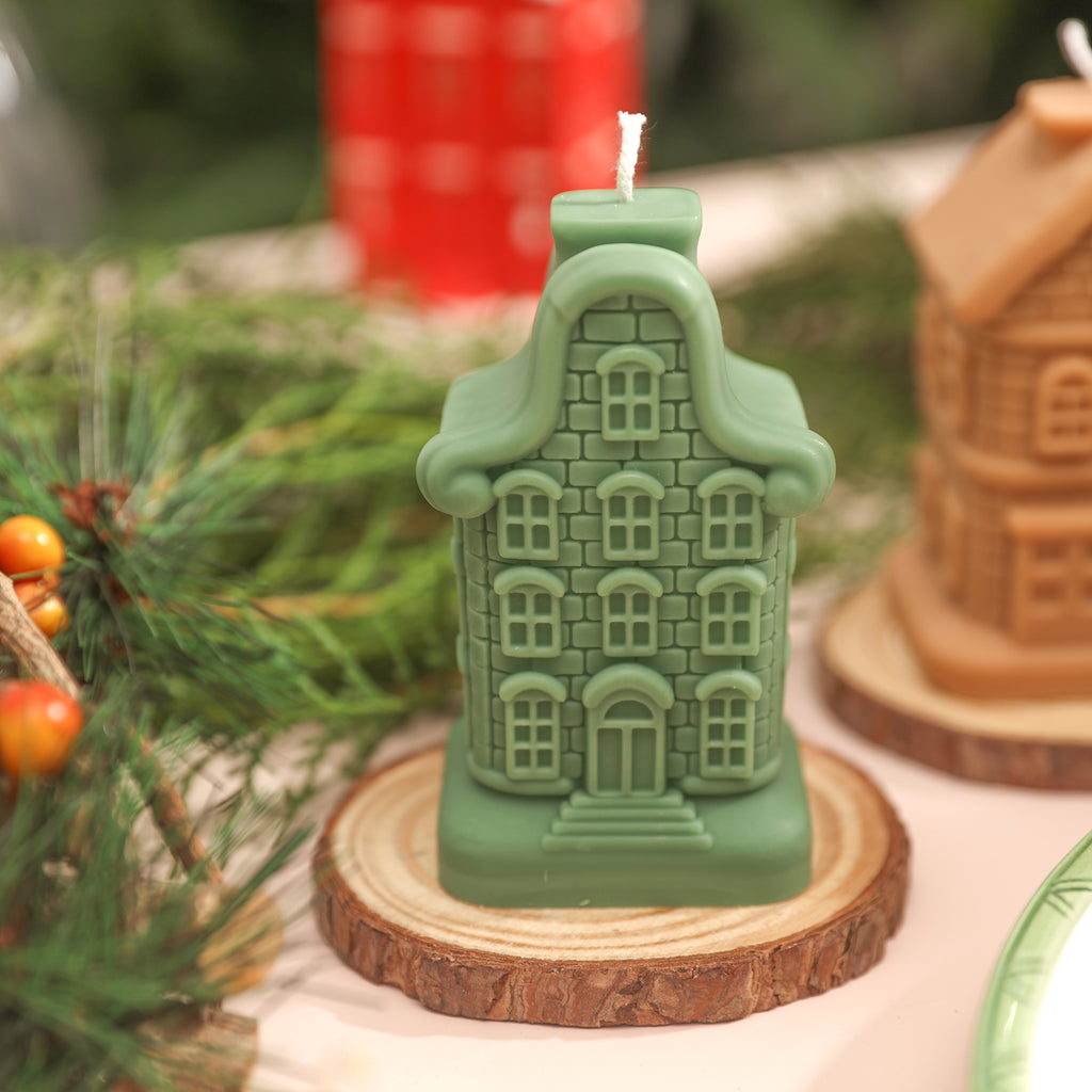 Green Nine Window House candle placed on wooden base.