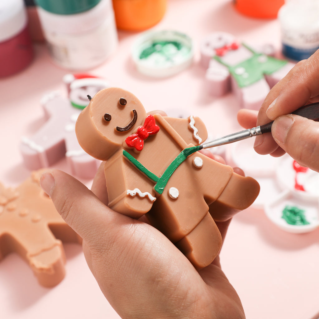Paint the bow tie red on the gingerbread man candle and paint the suspenders green, by Boowan Nciole.