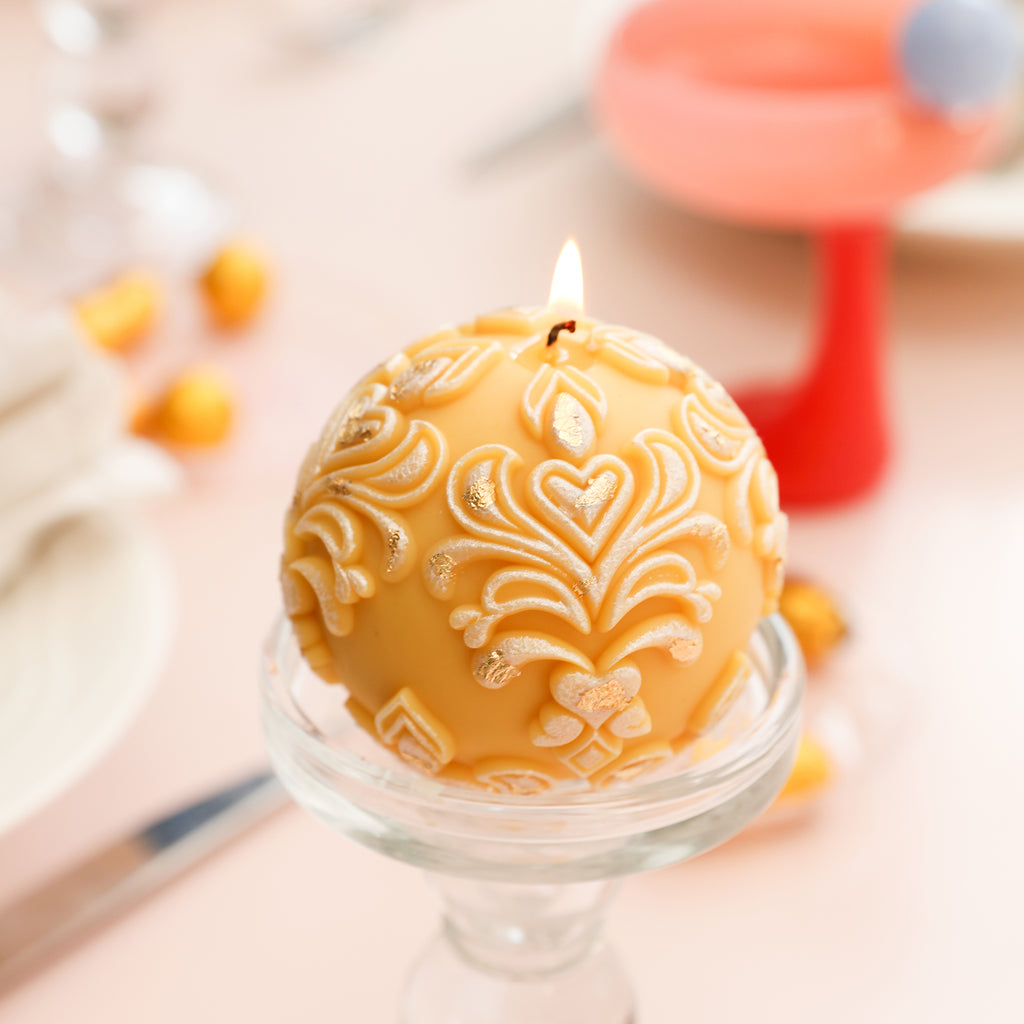 Lit orange sphere patterned relief candle, creating a warm ambiance.