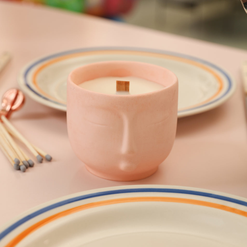 Pink candle jar with human face placed on the dining table-Boowan Nicole