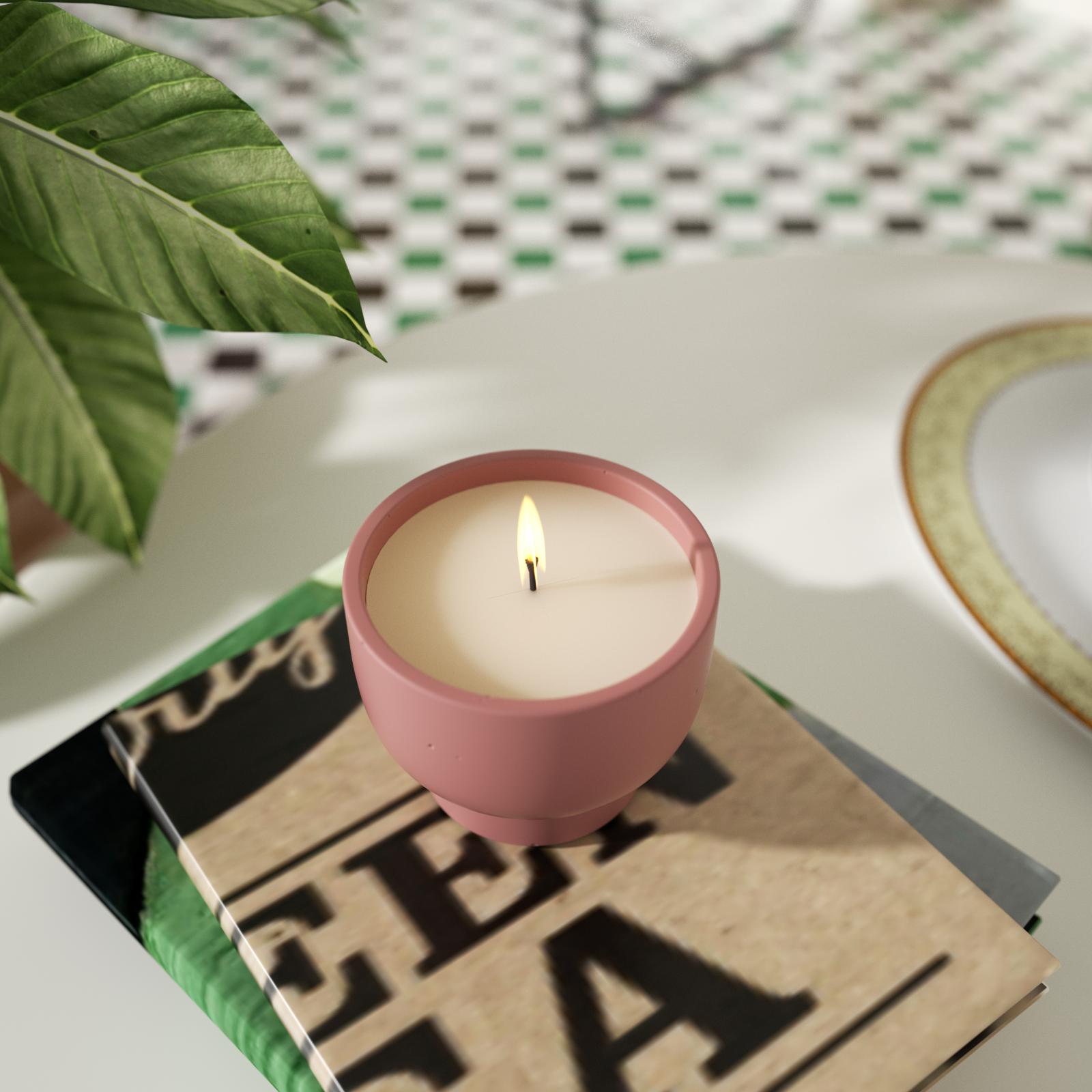 A candle is burning slowly in a bowl-shaped candle jar, placed on a book