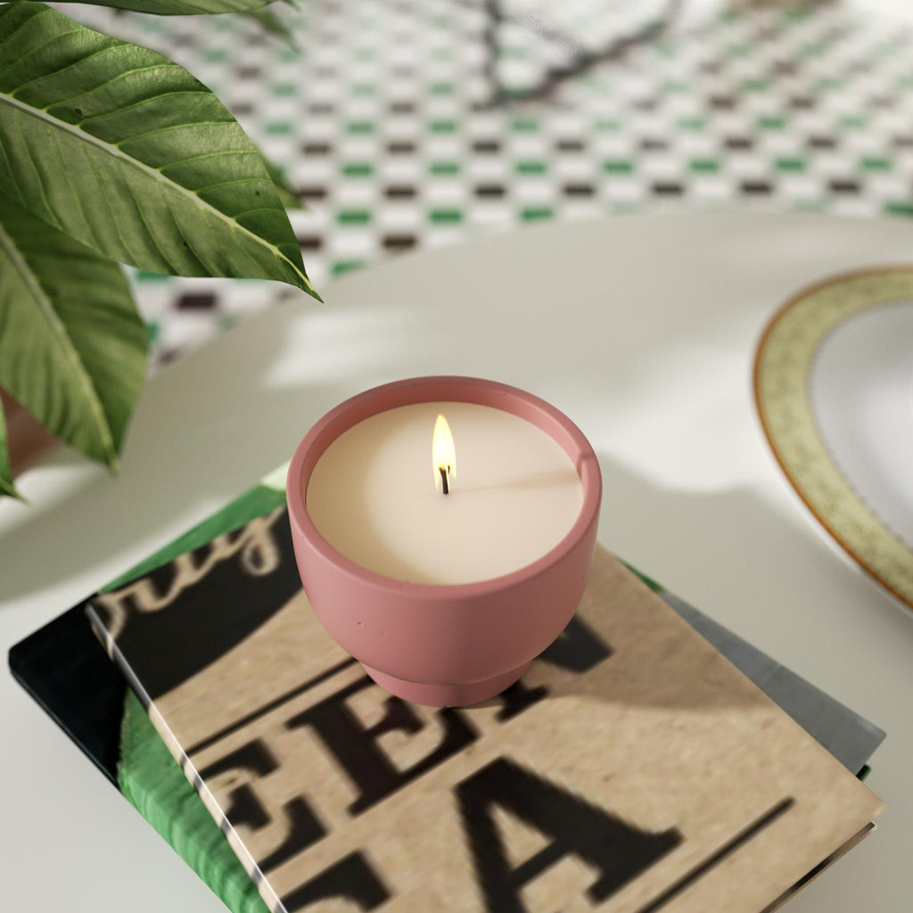 A candle is burning slowly in a bowl-shaped candle jar, placed on a book