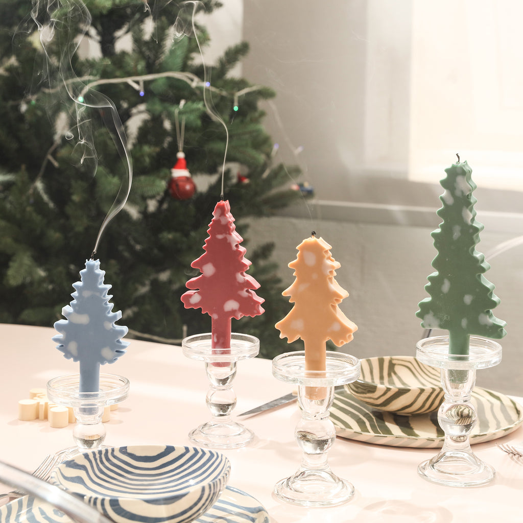 Four Christmas tree-shaped taper candles placed on the table candlesticks provide a festive atmosphere for the meal.