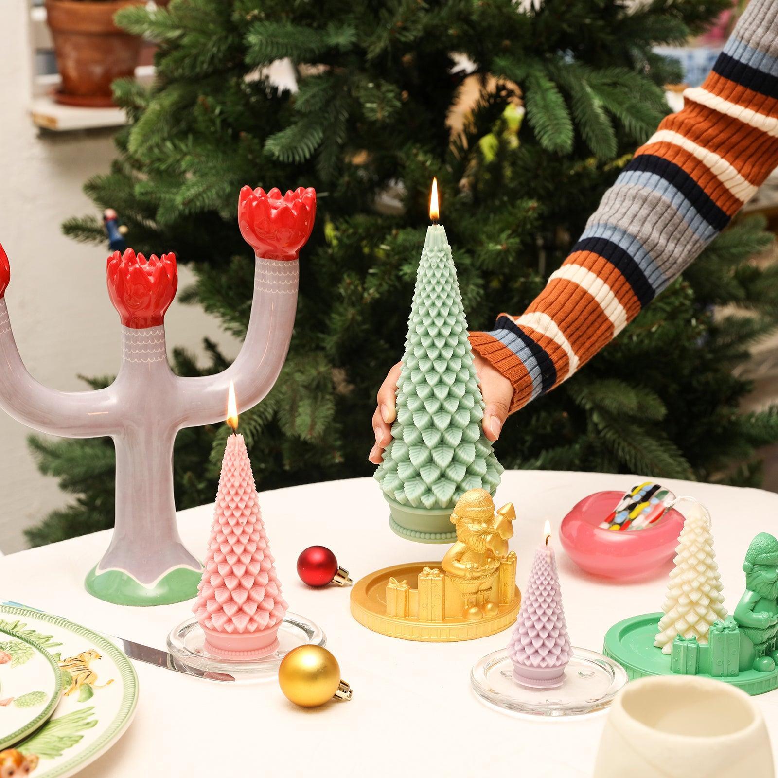 Place the green tapered Christmas tree candles on the table, which is full of Christmas decorations-Boowan Nicole