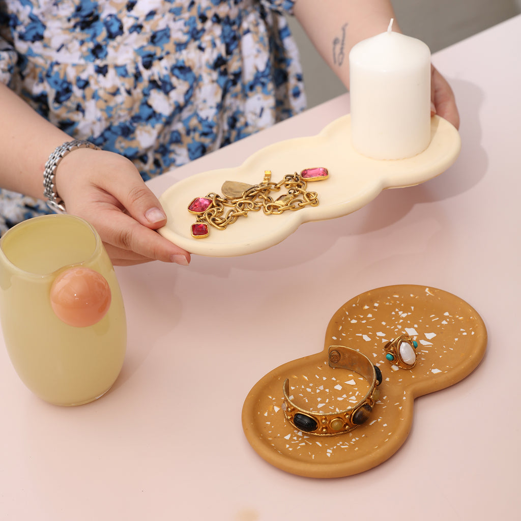 Necklaces and candles are placed on the white Double-Nut Peanut-Shaped Tray, and bracelets and rings are placed on the yellow terrazzo tray - Boowan Nicole