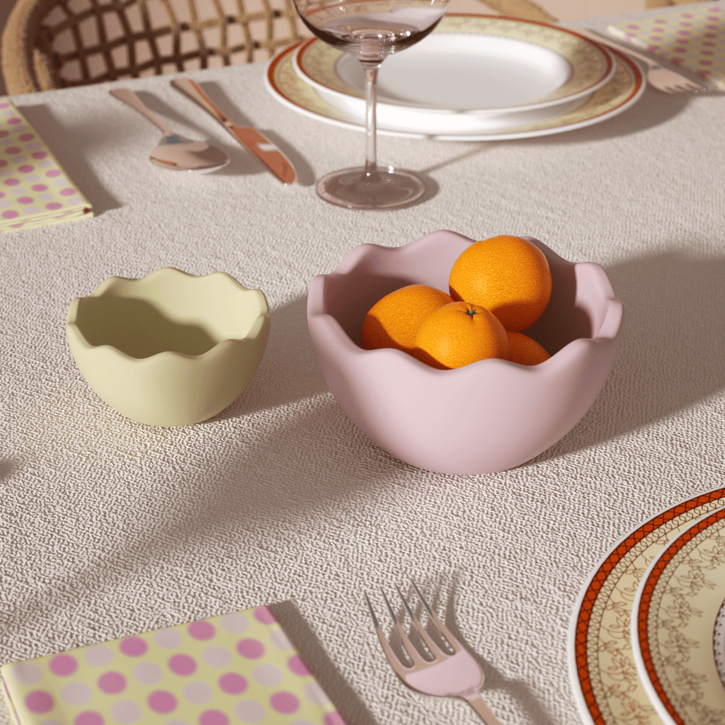 Two eggshell bowls, one large and one small, are placed on the dining table, one of which holds oranges