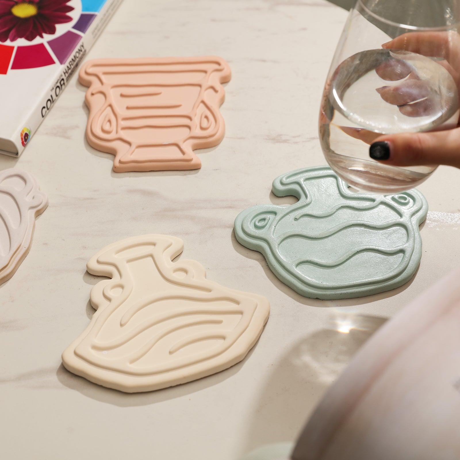 Three coasters are placed on the table, and the water glass is picked up from the coasters. Designed by Boowan Nicole.