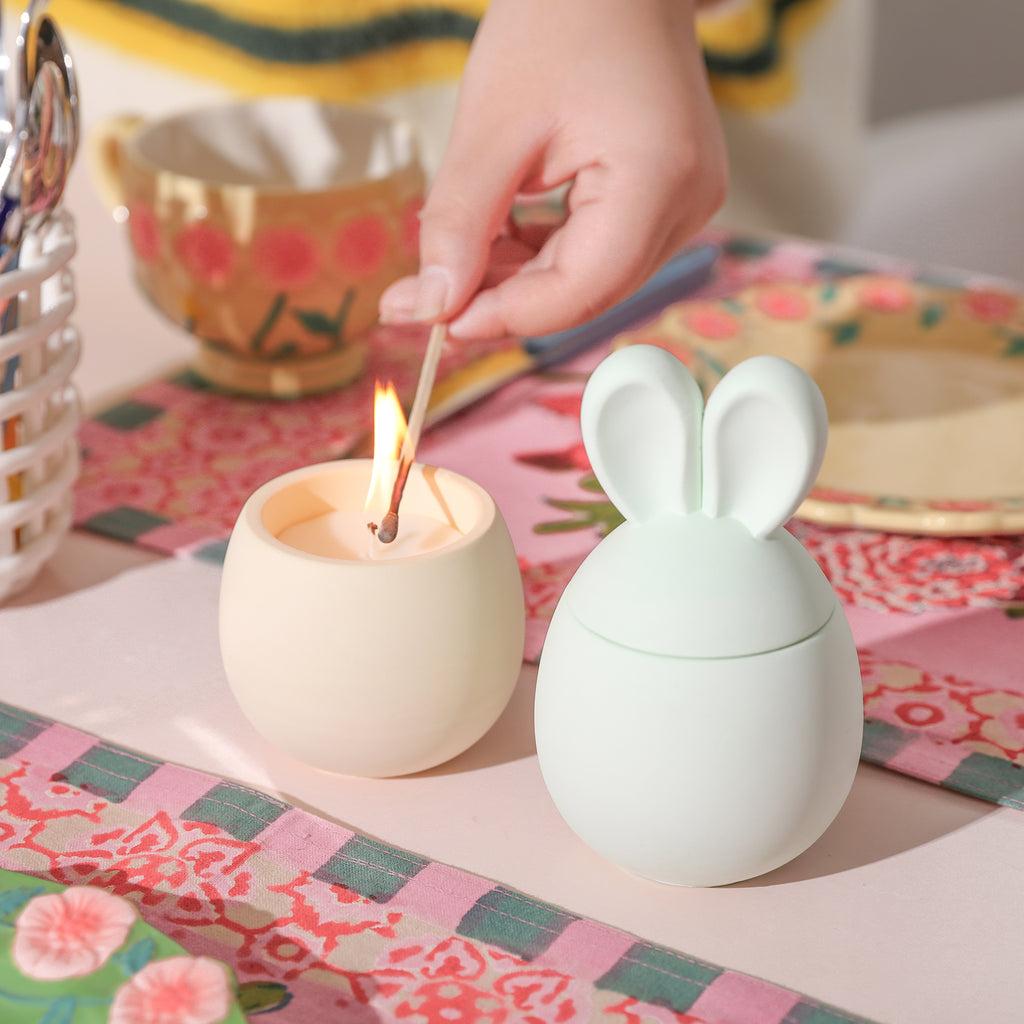 Two Easter Bunny candle jars, one of which is being lit