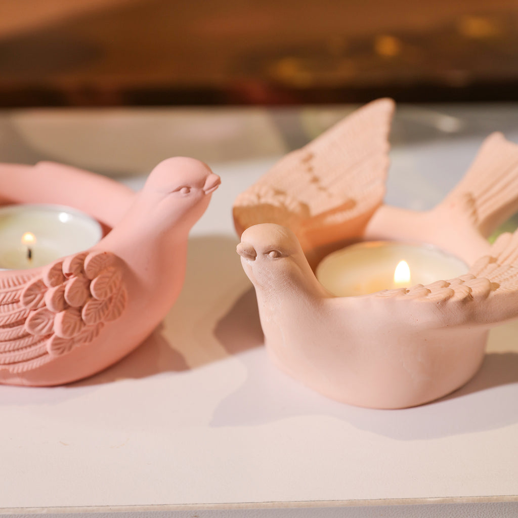A dynamic scene where candles within two bird-shaped holders are gracefully burning, casting a warm glow.