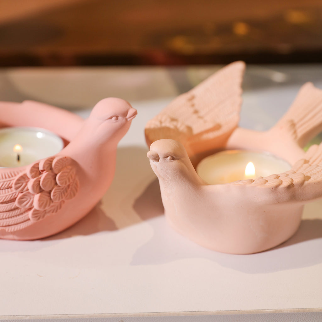 Two pink tealight candle holders with burning candles.