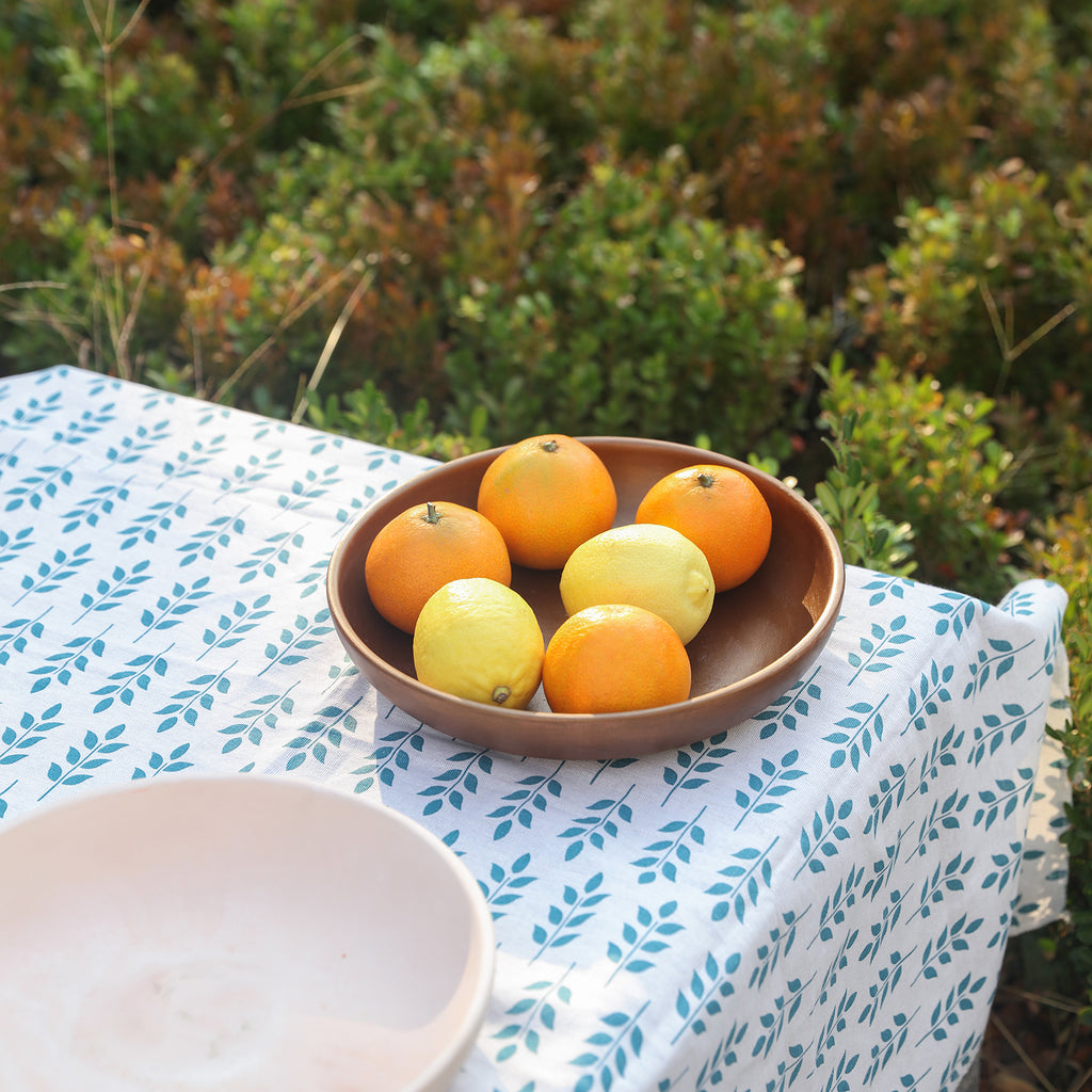 Round trays of lemons and oranges sit on an outdoor table.