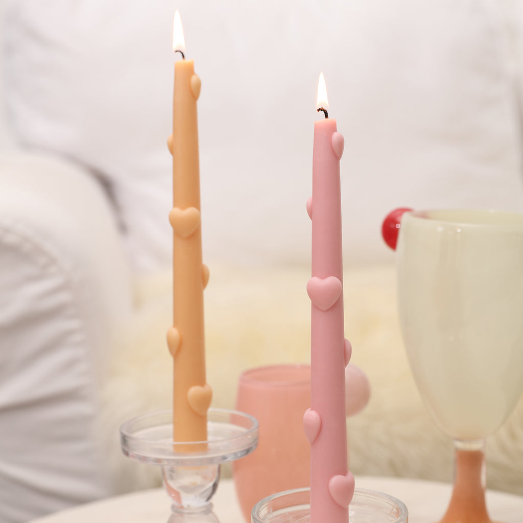 Witness the captivating display of burning yellow and pink Love Heart Taper Candles, radiating a harmonious blend of colors.