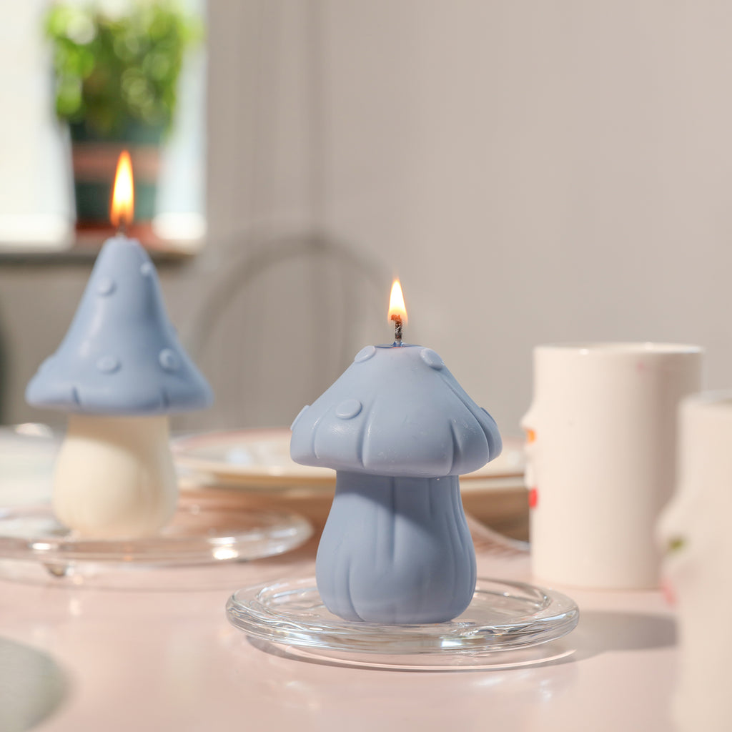 A blue candle in the shape of a mushroom is lit on a crystal tray on the dining table.