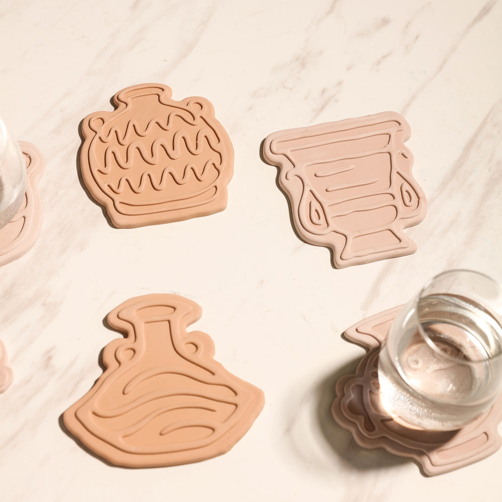 Four coasters of different shapes are placed on the table, designed by Boowan Nicole.