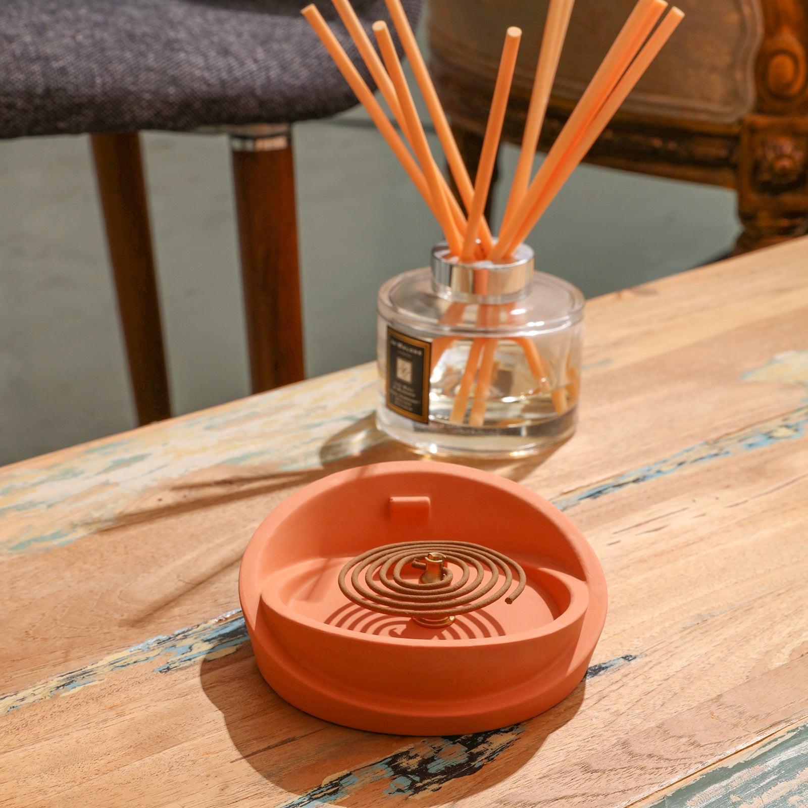There is a coil of incense in the reddish-brown Sail-Shape Incense Holder, and a smokeless aromatherapy diffuser behind it - Boowan Nicole