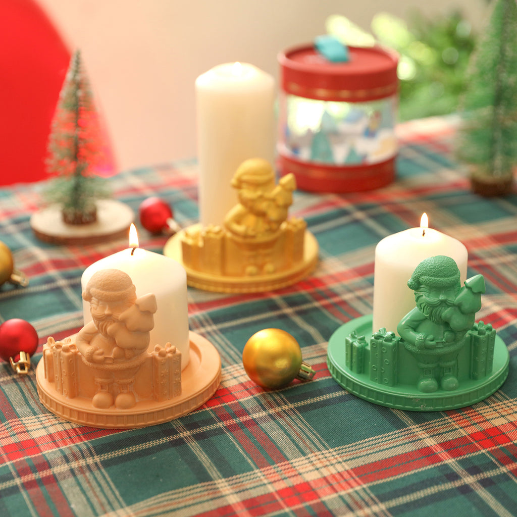 Santa Claus candle holders in yellow, green and gold colors are placed on the dining table, with white candles placed on them respectively, designed by Boowan Nicole.