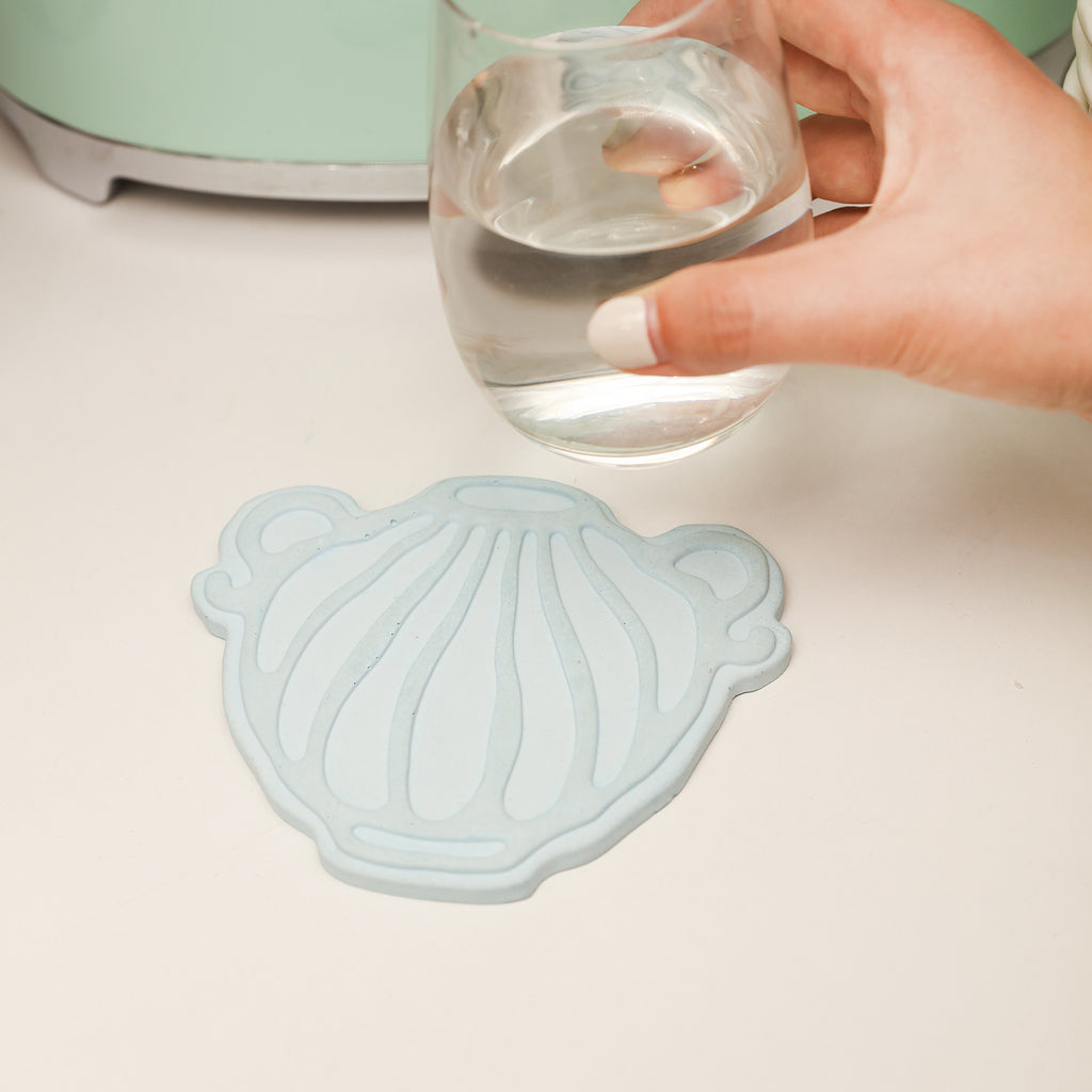 Place the water bottle on the blue wave-patterned water bottle-shaped coaster next to the book to accompany your daily life, designed by Boowan Nicole.