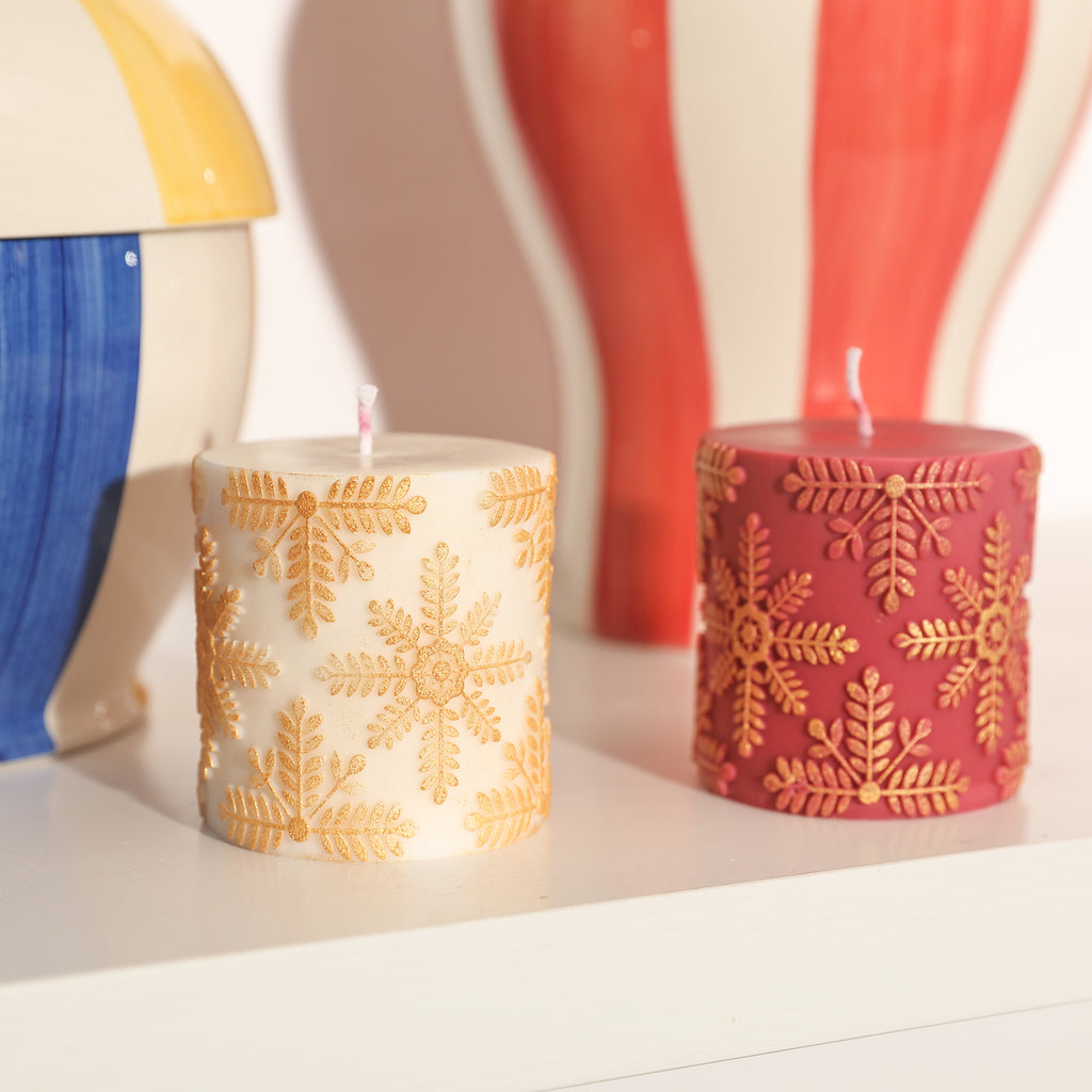 Short red and white gold snowflake relief candles are placed on the bookshelf as a home decoration.
