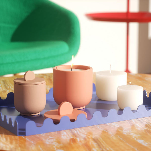 Lighting a candle in a candle jar with candle refills next to it