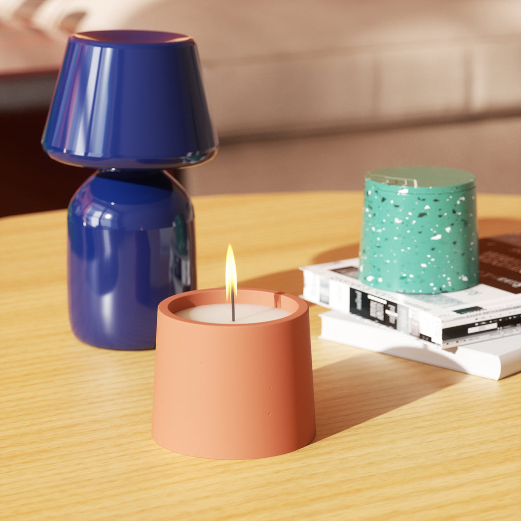 Blue vase, a glowing candle in a jar, beside a green candle jar made with Boowannite and terrazzo, showcasing Boowannicole's craftsmanship.