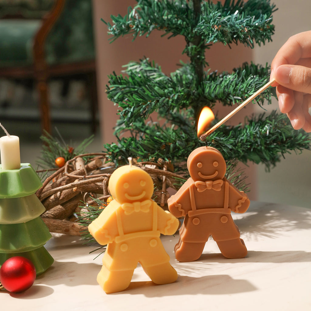 Light the gingerbread man candle next to the pine branch, designed by Boowan Nciole.