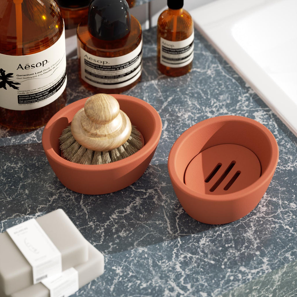 There are two reddish-brown oval soap dishes on the bathroom sink, one of which holds a shaving brush.