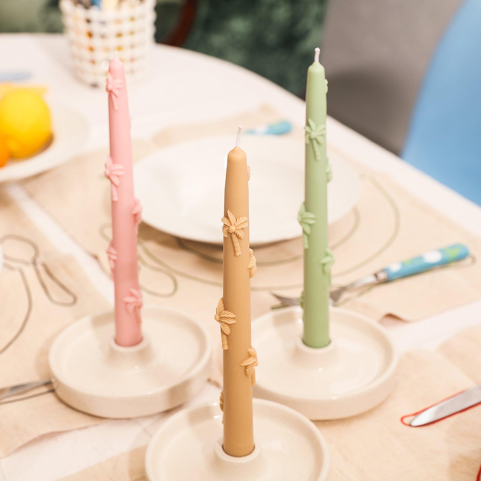 Palm tree embossed taper candles placed on the dining table.