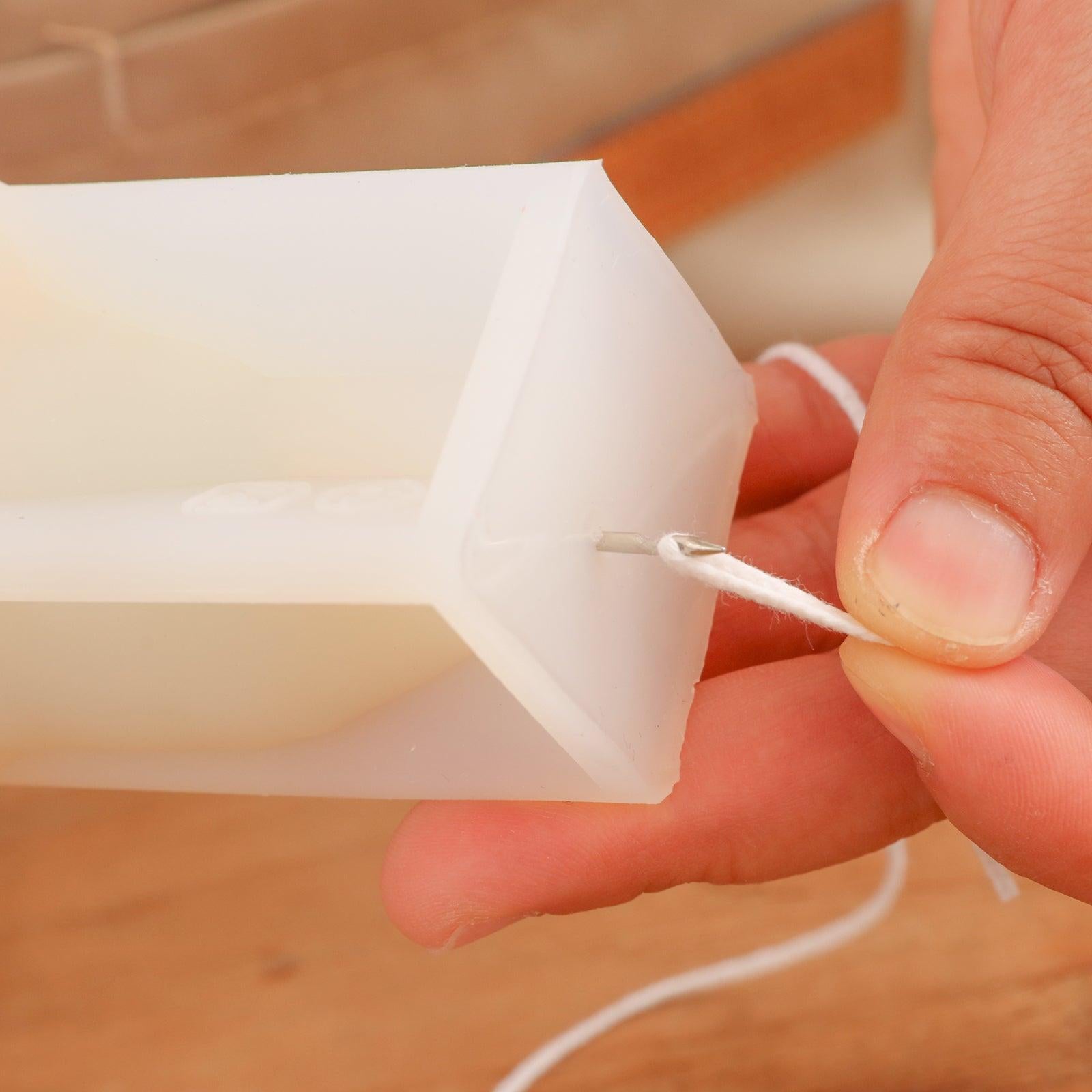 Shows how the threading tool threads candle wicks in silicone candle molds.