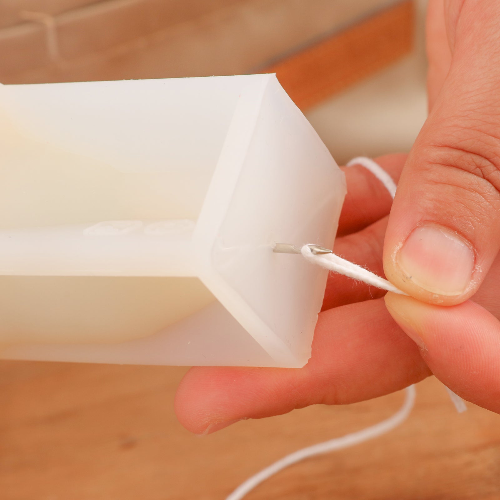 Shows how the threading tool threads candle wicks in silicone candle molds.