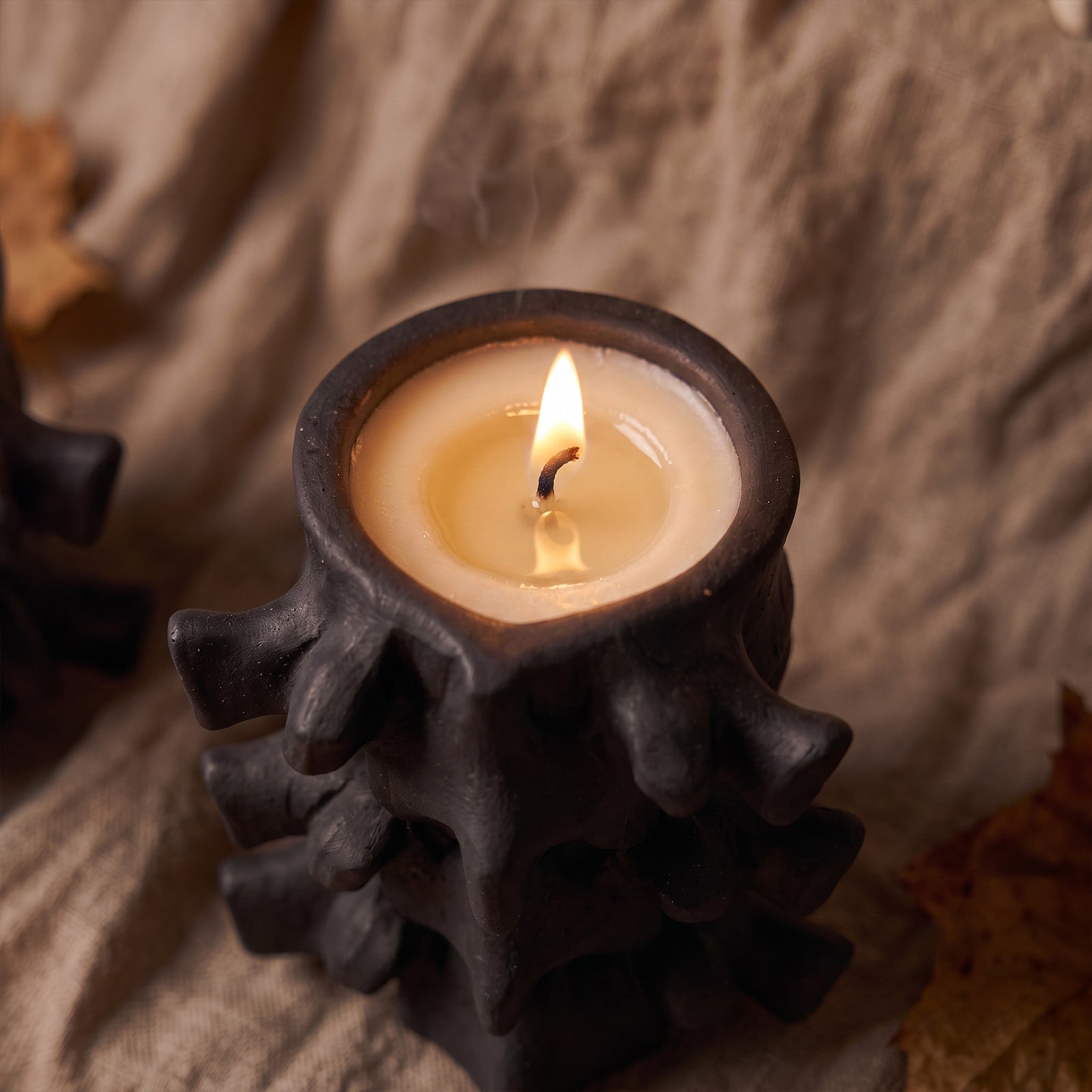 Close-up view of burning black Haunted Spine spine-shaped candle jar - Boowan Nicole