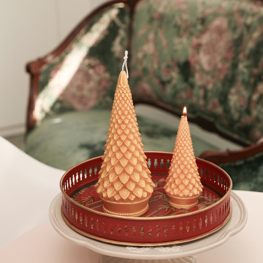 Two Conical Christmas tree candles, one large and one small, slowly burning in the tray—Boowan Nicole