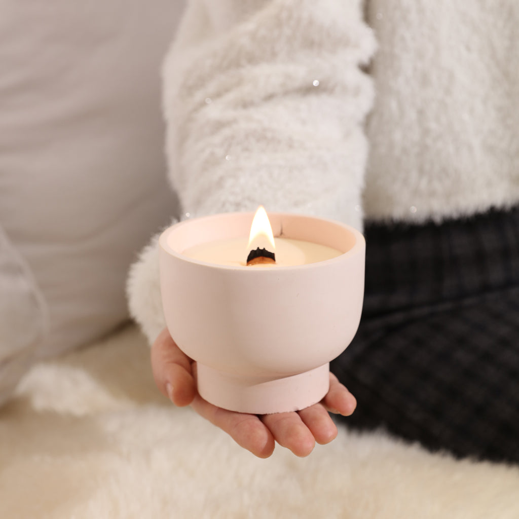 Burning bowl-shaped candle jar placed in hand for display